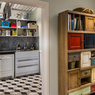 ウェリントンの大きいヴィクトリアン調のおしゃれな洗濯室 (スロップシンク、御影石カウンター、青い壁、磁器タイルの床、左右配置の洗濯機・乾燥機) の写真