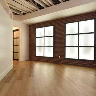 Exemple d'un grand sous-sol tendance enterré avec salle de jeu, un mur blanc, un sol en vinyl, une cheminée standard, un manteau de cheminée en bois et un sol beige.