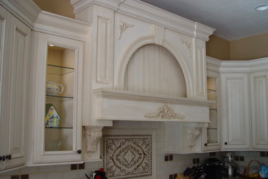 Inspiration for a mid-sized timeless u-shaped light wood floor eat-in kitchen remodel in Tampa with a drop-in sink, flat-panel cabinets, white cabinets, granite countertops, beige backsplash, mosaic tile backsplash, stainless steel appliances and an island