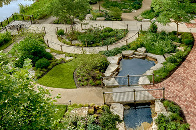 На фото: большой летний регулярный сад на внутреннем дворе в классическом стиле с садовой дорожкой или калиткой, полуденной тенью и покрытием из каменной брусчатки