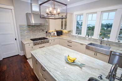 Mid-sized beach style l-shaped medium tone wood floor eat-in kitchen photo in Miami with a farmhouse sink, shaker cabinets, white cabinets, quartzite countertops, multicolored backsplash, glass tile backsplash, stainless steel appliances and an island