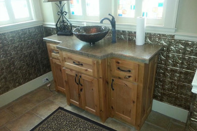 Mid-sized 3/4 brown tile and ceramic tile ceramic tile bathroom photo in Oklahoma City with a vessel sink, recessed-panel cabinets, medium tone wood cabinets, solid surface countertops and white walls
