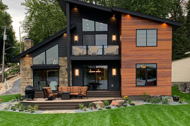 Inspiration for a large contemporary black two-story mixed siding and clapboard house exterior remodel in Minneapolis with a shed roof, a shingle roof and a black roof