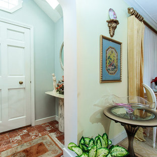 Réalisation d'une petite porte d'entrée bohème avec un mur bleu, un sol en carrelage de céramique, une porte simple, une porte blanche et un sol rouge.