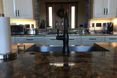 Example of a classic kitchen design in Other with a farmhouse sink, raised-panel cabinets, distressed cabinets, quartz countertops, stainless steel appliances and an island