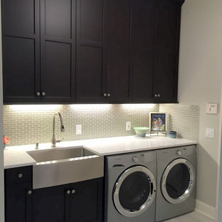 Ejemplo de lavadero multiusos y en L, tradicional renovado, de tamaño medio, con fregadero sobremueble, armarios con paneles empotrados, puertas de armario de madera en tonos medios, encimera de cuarzo compacto, paredes grises, suelo de baldosas de porcelana y lavadora y secadora juntas