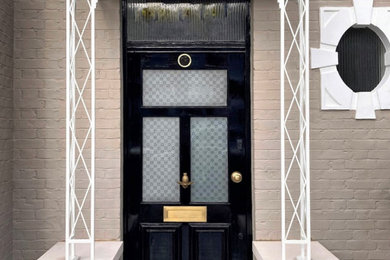 Photo of a small traditional porch in London with beige walls, ceramic flooring, a single front door and a black front door.