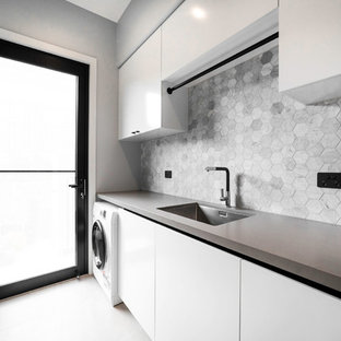 Design ideas for a medium sized modern galley utility room in Brisbane with a built-in sink, flat-panel cabinets, white cabinets, concrete worktops, grey walls, concrete flooring, a side by side washer and dryer, grey floors and white worktops.