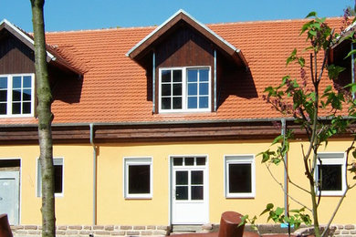 Großes, Zweistöckiges Modernes Reihenhaus mit Putzfassade, gelber Fassadenfarbe, Satteldach und Ziegeldach in Leipzig