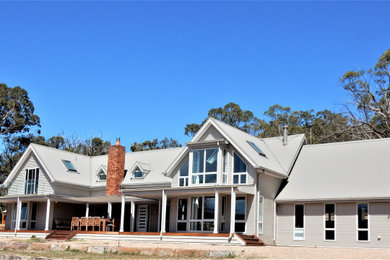 Diseño de fachada de casa gris y gris actual grande de dos plantas con revestimiento de metal y tejado a dos aguas