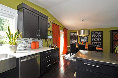 Eat-in kitchen - large transitional l-shaped dark wood floor eat-in kitchen idea in Seattle with a farmhouse sink, shaker cabinets, black cabinets, stainless steel countertops, multicolored backsplash, matchstick tile backsplash, stainless steel appliances and an island