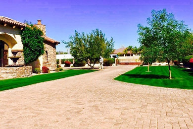 This is an example of a large mediterranean front yard stone landscaping in Phoenix.