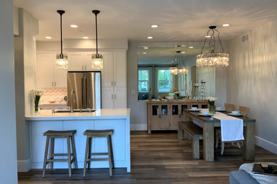 Example of a small minimalist u-shaped vinyl floor eat-in kitchen design in Los Angeles with a single-bowl sink, recessed-panel cabinets, white cabinets, quartz countertops, mosaic tile backsplash, stainless steel appliances, a peninsula and white countertops