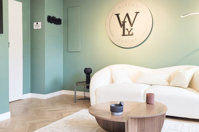 Réalisation d'un petit salon design avec un mur vert, sol en stratifié, un téléviseur fixé au mur et un sol beige.