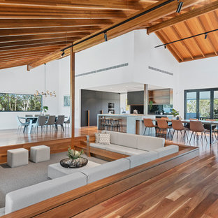 This is an example of a large contemporary open concept family room in Brisbane with medium hardwood floors, white walls and a wood fireplace surround.