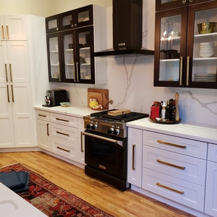 Idéer för mellanstora funkis vitt skafferier, med en undermonterad diskho, skåp i shakerstil, vita skåp, bänkskiva i kvarts, vitt stänkskydd, stänkskydd i sten, svarta vitvaror, ljust trägolv, en köksö och gult golv