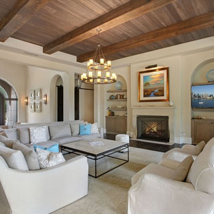 Immagine di un grande soggiorno mediterraneo aperto con sala formale, pareti beige, parquet scuro, camino classico, cornice del camino in pietra, nessuna TV e pavimento grigio
