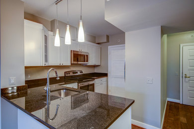 Example of a mid-sized trendy l-shaped medium tone wood floor kitchen design in DC Metro with an undermount sink, shaker cabinets, white cabinets, granite countertops, stainless steel appliances and no island