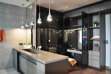 Walk-in closet - large contemporary gender-neutral medium tone wood floor walk-in closet idea in New York with flat-panel cabinets and gray cabinets