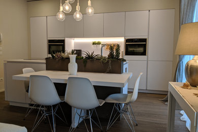 Esempio di una grande cucina contemporanea con lavello sottopiano, ante lisce, ante bianche, top in quarzo composito, paraspruzzi bianco, paraspruzzi in quarzo composito, elettrodomestici in acciaio inossidabile, parquet scuro, pavimento marrone e top bianco