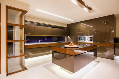 Photo of a mid-sized modern kitchen in Adelaide with an undermount sink, flat-panel cabinets, medium wood cabinets, glass benchtops, stainless steel appliances, limestone floors and multiple islands.
