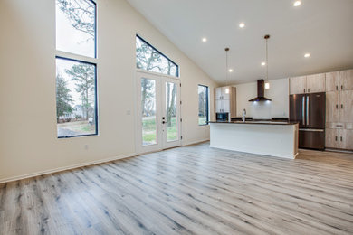 Minimalist beige floor and vaulted ceiling kitchen photo in DC Metro with flat-panel cabinets, light wood cabinets, granite countertops, black appliances, an island and brown countertops