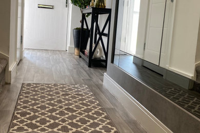 Design ideas for a small contemporary foyer in Manchester with white walls, a single front door, a white front door, grey floors and a feature wall.
