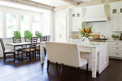Example of a trendy dark wood floor and brown floor eat-in kitchen design in Vancouver with recessed-panel cabinets, white cabinets, white backsplash, subway tile backsplash, an island and white countertops