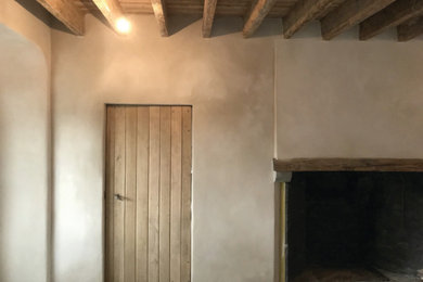 Réalisation d'un salon champêtre avec un mur beige, une cheminée standard et un manteau de cheminée en plâtre.