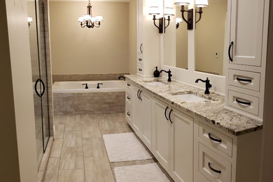 Inspiration for a contemporary beige floor corner bathtub remodel in Chicago with recessed-panel cabinets, white cabinets, an undermount sink, marble countertops and a hinged shower door