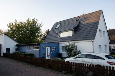 Imagen de fachada de casa blanca y gris actual de dos plantas con revestimiento de estuco, tejado a dos aguas y tejado de teja de barro