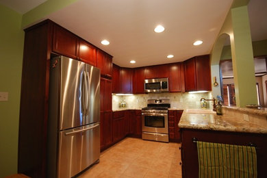Example of a classic u-shaped eat-in kitchen design in San Diego with a drop-in sink, recessed-panel cabinets, dark wood cabinets, granite countertops, beige backsplash, stone tile backsplash and stainless steel appliances