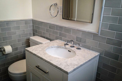Example of a mid-sized classic gray tile and ceramic tile powder room design in San Diego with shaker cabinets, white cabinets, a two-piece toilet, white walls, an undermount sink and marble countertops