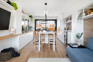 Design ideas for a medium sized scandinavian single-wall open plan kitchen in Barcelona with a submerged sink, flat-panel cabinets, white cabinets, engineered stone countertops, white splashback, wood splashback, stainless steel appliances, medium hardwood flooring, an island and white worktops.