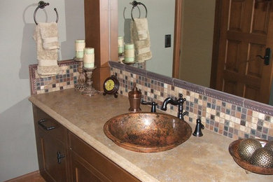 Photo of a mid-sized traditional bathroom in Seattle with recessed-panel cabinets, medium wood cabinets, beige walls, a vessel sink and limestone benchtops.