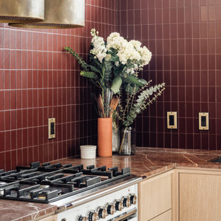 Mittelgroße Mid-Century Wohnküche in L-Form mit integriertem Waschbecken, flächenbündigen Schrankfronten, hellen Holzschränken, Marmor-Arbeitsplatte, Küchenrückwand in Rot, Rückwand aus Glasfliesen, weißen Elektrogeräten, Terrazzo-Boden, Halbinsel, grauem Boden, roter Arbeitsplatte und freigelegten Dachbalken in Salt Lake City