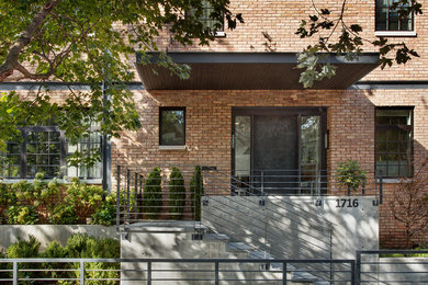 Large contemporary red two-story brick exterior home idea in Chicago
