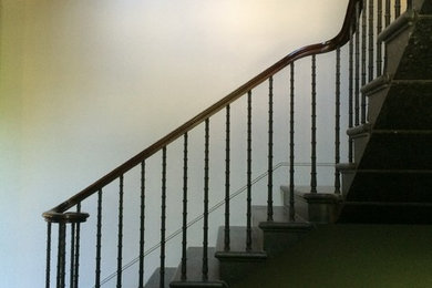 Photo of a large traditional l-shaped metal railing staircase with limestone treads and limestone risers.