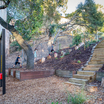 Timber tie steps lead to lower terrace, with stumps running up hillside as alter