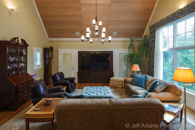 Mid-sized elegant enclosed medium tone wood floor family room photo in Boston with beige walls, no fireplace and a wall-mounted tv