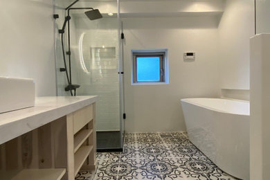 東京23区にある高級な中くらいなモダンスタイルのおしゃれなマスターバスルーム (オープンシェルフ、白いキャビネット、置き型浴槽、コーナー設置型シャワー、一体型トイレ	、白いタイル、サブウェイタイル、白い壁、セメントタイルの床、ベッセル式洗面器、ライムストーンの洗面台、マルチカラーの床、開き戸のシャワー、白い洗面カウンター、トイレ室、洗面台1つ、造り付け洗面台、塗装板張りの天井、塗装板張りの壁) の写真