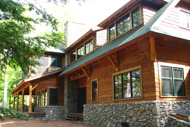 This is an example of a large country two-storey brown exterior in Other with wood siding and a shed roof.