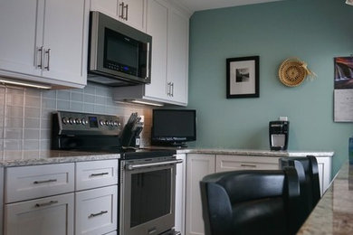 Example of a small transitional galley porcelain tile and gray floor eat-in kitchen design in Boston with a single-bowl sink, shaker cabinets, white cabinets, quartz countertops, gray backsplash, glass tile backsplash, stainless steel appliances and a peninsula