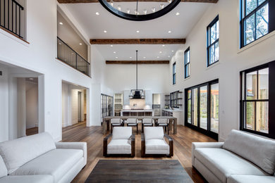 Inspiration for an expansive contemporary open concept family room in Detroit with white walls, medium hardwood floors, a standard fireplace, a stone fireplace surround, a wall-mounted tv and brown floor.