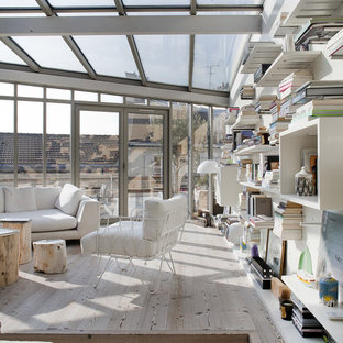 Exempel på ett mellanstort modernt allrum med öppen planlösning, med ett bibliotek, vita väggar och ljust trägolv