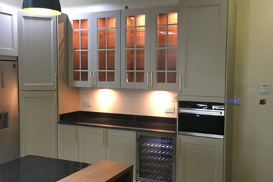 Design ideas for a large classic cream and black u-shaped enclosed kitchen in Other with a belfast sink, recessed-panel cabinets, beige cabinets, granite worktops, white splashback, porcelain splashback, coloured appliances, terracotta flooring, an island, grey floors, black worktops, a drop ceiling and feature lighting.