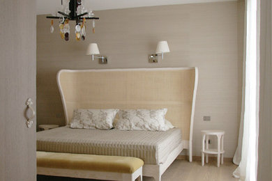 Modelo de dormitorio contemporáneo de tamaño medio con paredes beige, suelo de madera clara y papel pintado