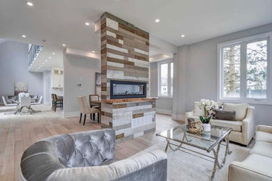Living room - mid-sized transitional formal and open concept light wood floor and beige floor living room idea in Toronto with gray walls, a two-sided fireplace and a wood fireplace surround