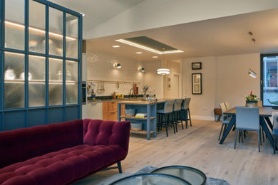 ダブリンにある高級な中くらいな北欧スタイルのおしゃれなキッチン (中間色木目調キャビネット、淡色無垢フローリング、三角天井) の写真