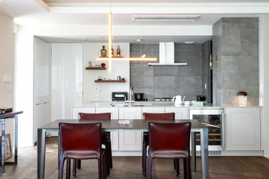 Esempio di una cucina minimalista con lavello sottopiano, ante a filo, ante bianche, top in superficie solida, paraspruzzi grigio, penisola, pavimento marrone e top bianco